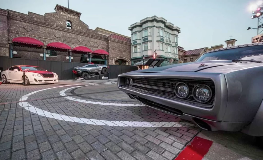 Carros em exibição na atração inspirada em Velozes e Furiosos com cenário urbano ao fundo.