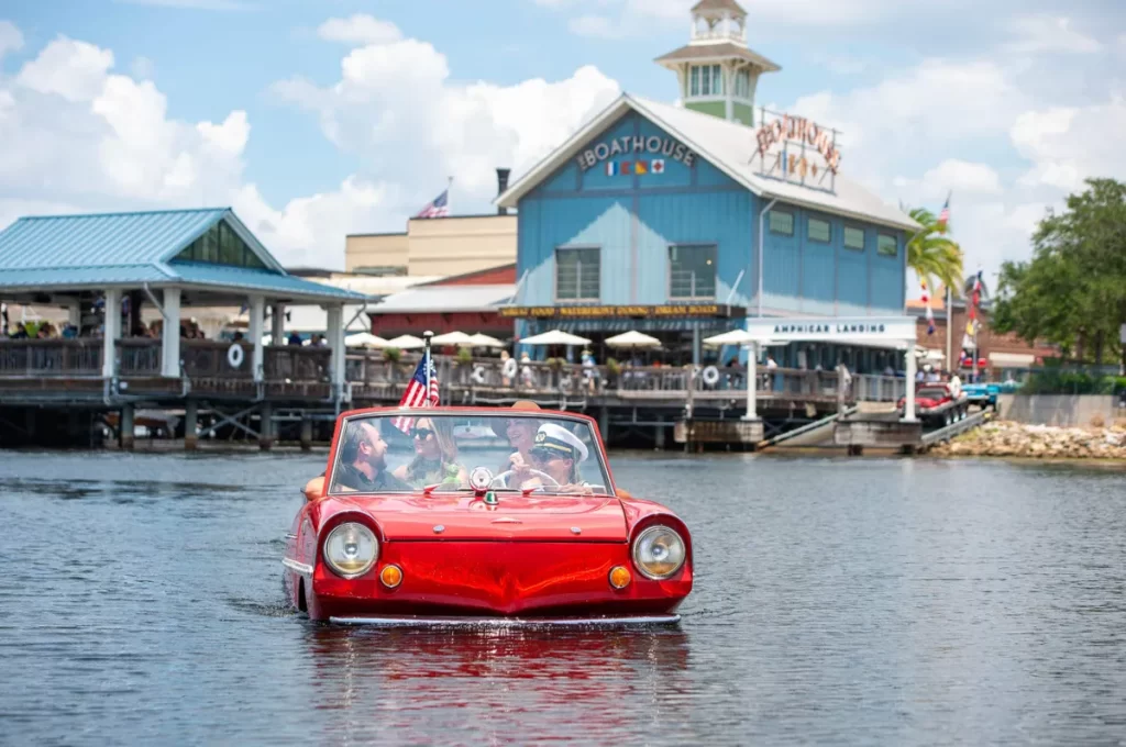 Carro anfíbio vermelho navegando em um lago com uma família a bordo
