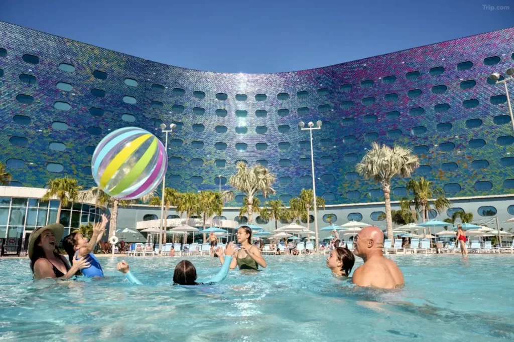 Família se divertindo na piscina do Universal Terra Luna Resort com fachada colorida ao fundo.