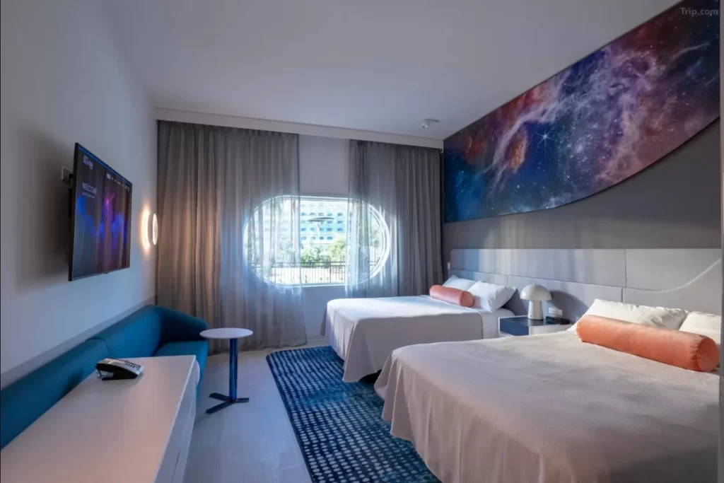 Interior do quarto duplo no Universal Stella Nova Hotel, com tema galáctico e janelas arredondadas.