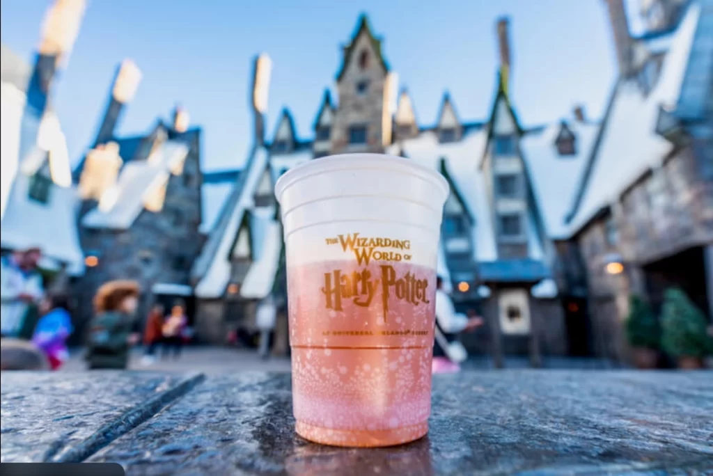 Copo de Butterbeer com logo do mundo mágico de Harry Potter em frente às lojas de Hogsmeade.