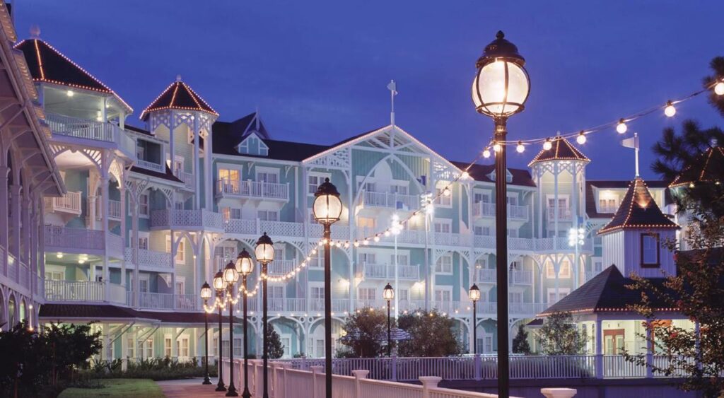 Fachada do Disney’s Beach Club Resort ao anoitecer, com lâmpadas decorativas.