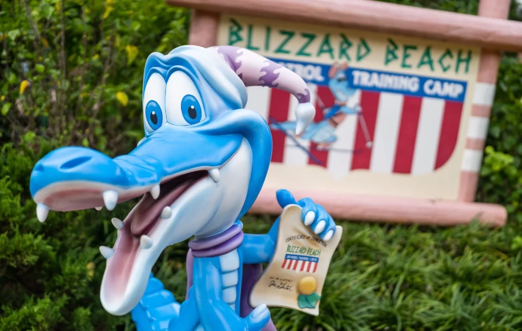Ice Gator, mascote do Blizzard Beach, segurando certificado em frente à placa do parque.
