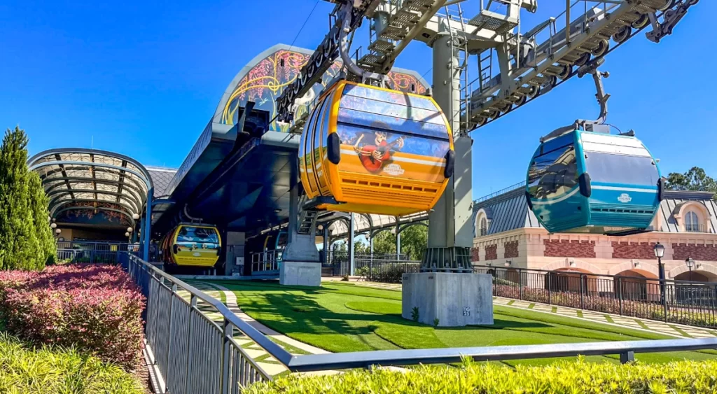 Cabine do Skyliner com Miguel (do filme Coco) saindo da estação do Epcot.