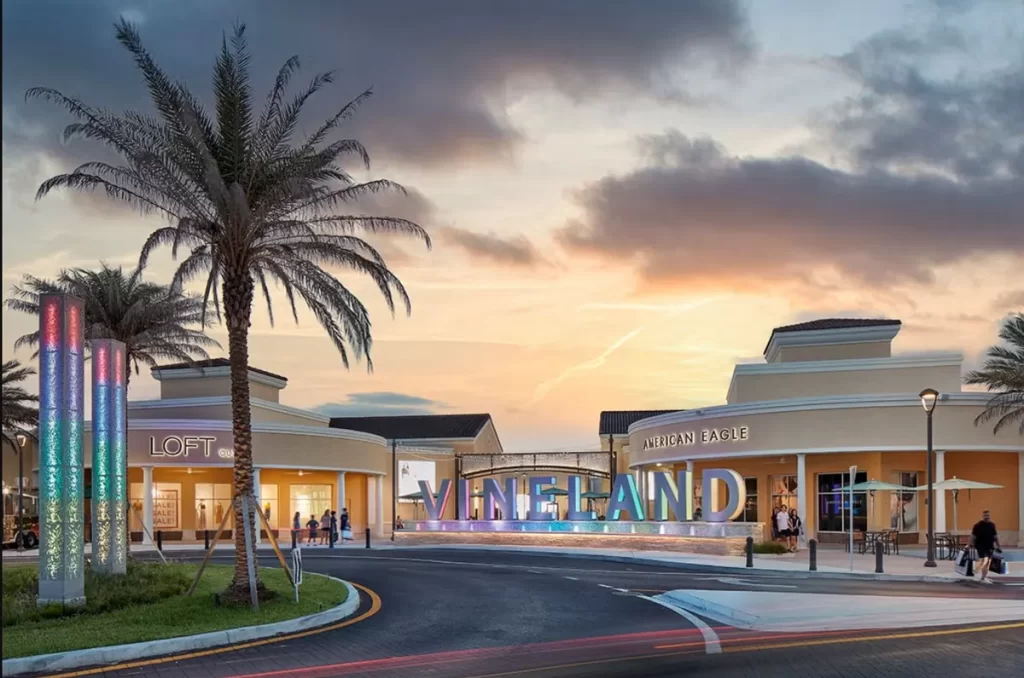 Outlet Premium Orlando: Fachada iluminada do Vineland Premium Outlets com lojas como American Eagle e Loft ao fundo, em Orlando.