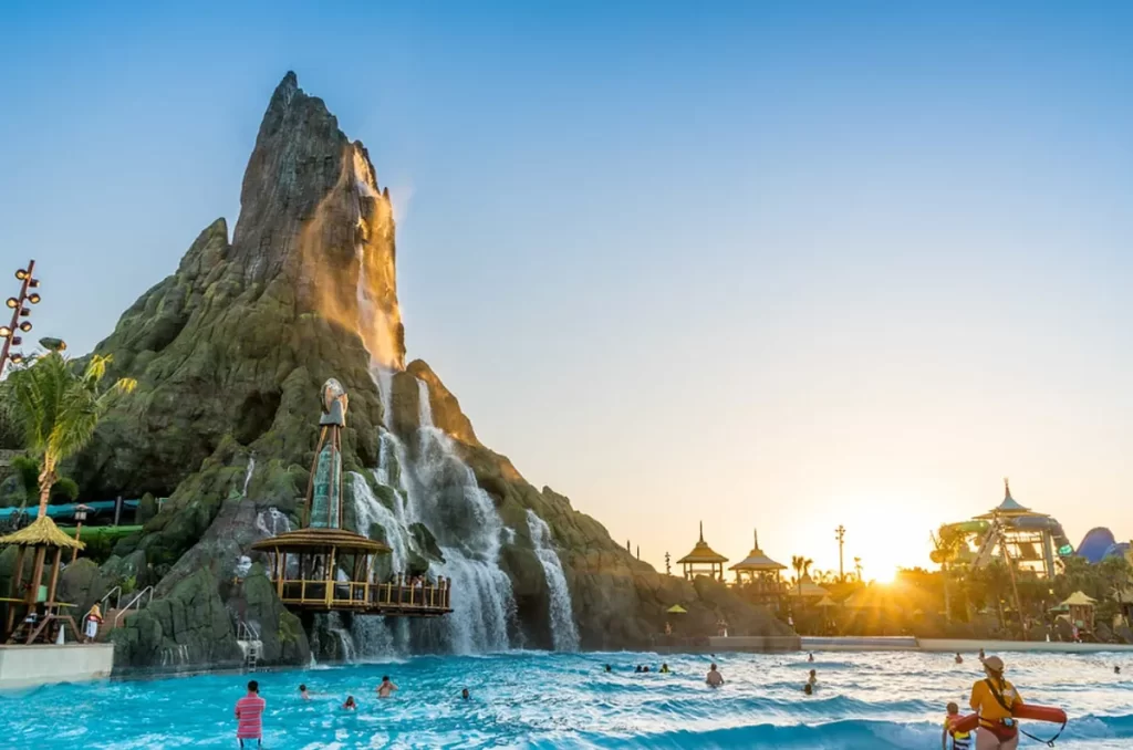 Pessoas aproveitam a piscina de ondas ao pôr do sol em frente ao vulcão do Volcano Bay.