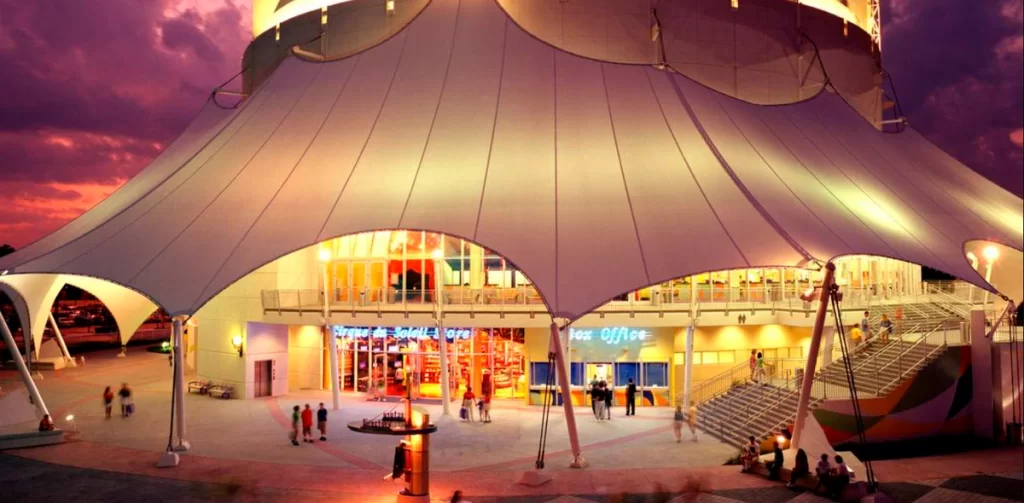 Fachada iluminada do teatro do Cirque du Soleil na Disney Springs ao entardecer.
