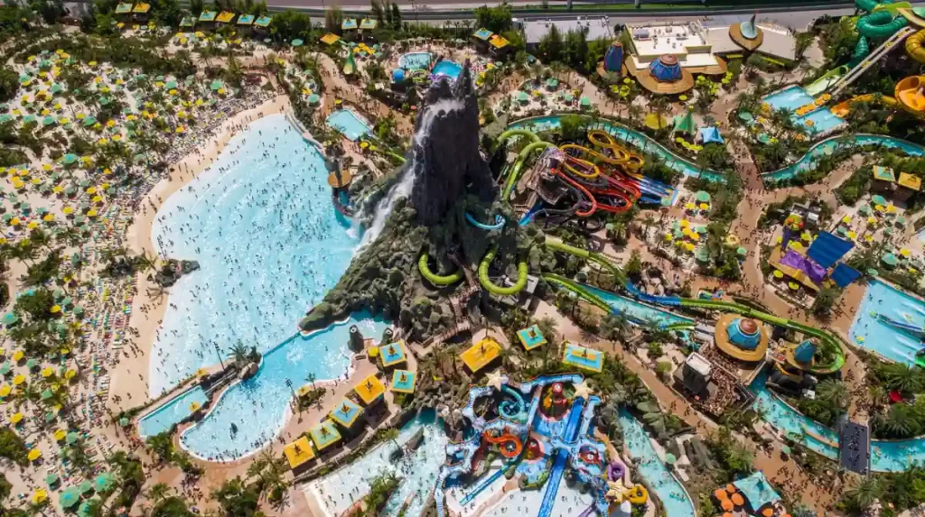 Vista aérea do parque aquático Volcano Bay com a piscina de ondas, escorregadores e o vulcão central.