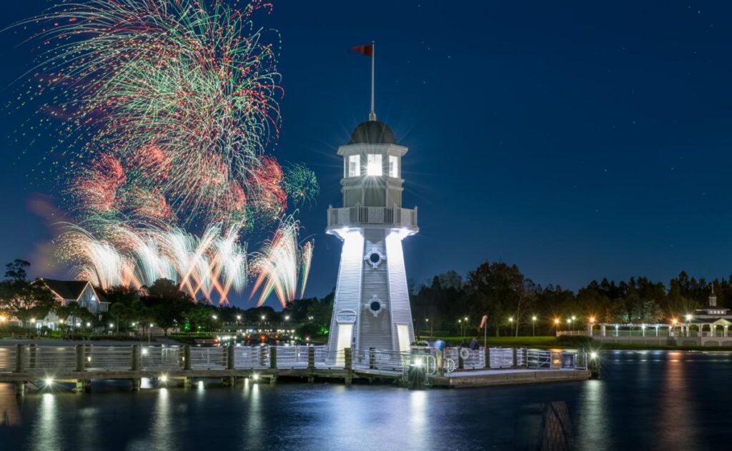 Farol do Yacht Club com queima de fogos ao fundo durante a noite.