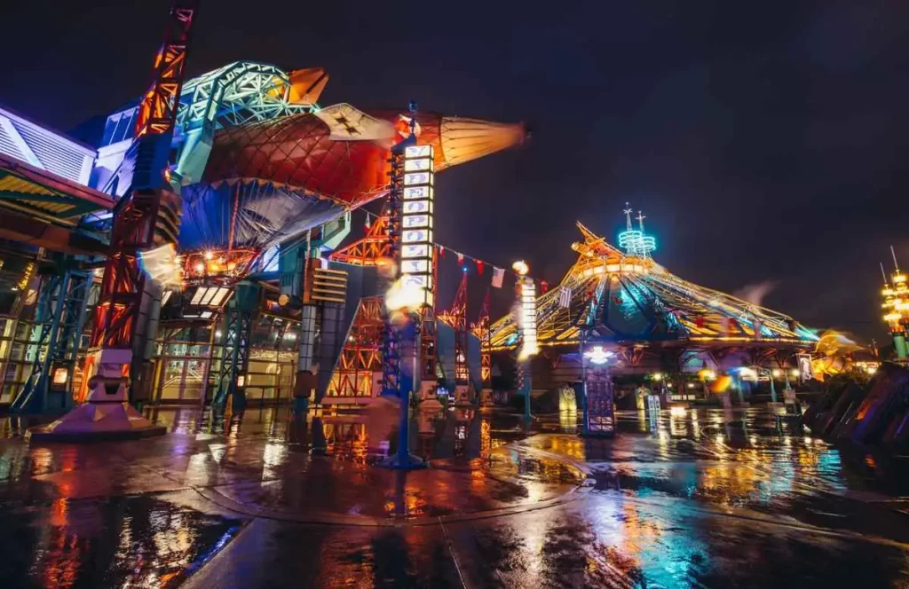 Discoveryland à noite com iluminação colorida refletida no chão molhado