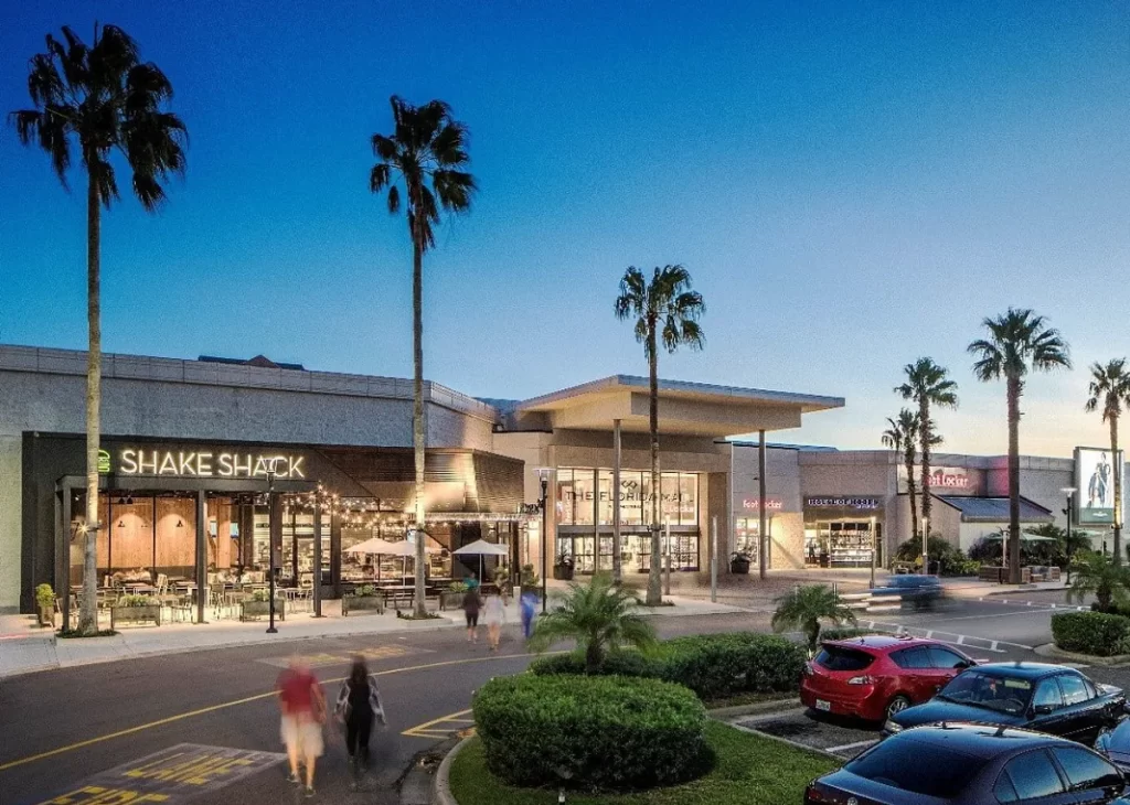 Entrada do Florida Mall ao anoitecer com loja Shake Shack ao lado