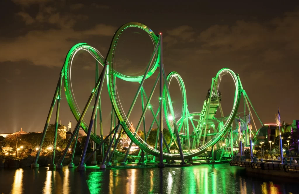 Montanha-russa The Incredible Hulk iluminada em verde à noite sobre a água no Universal’s Islands of Adventure