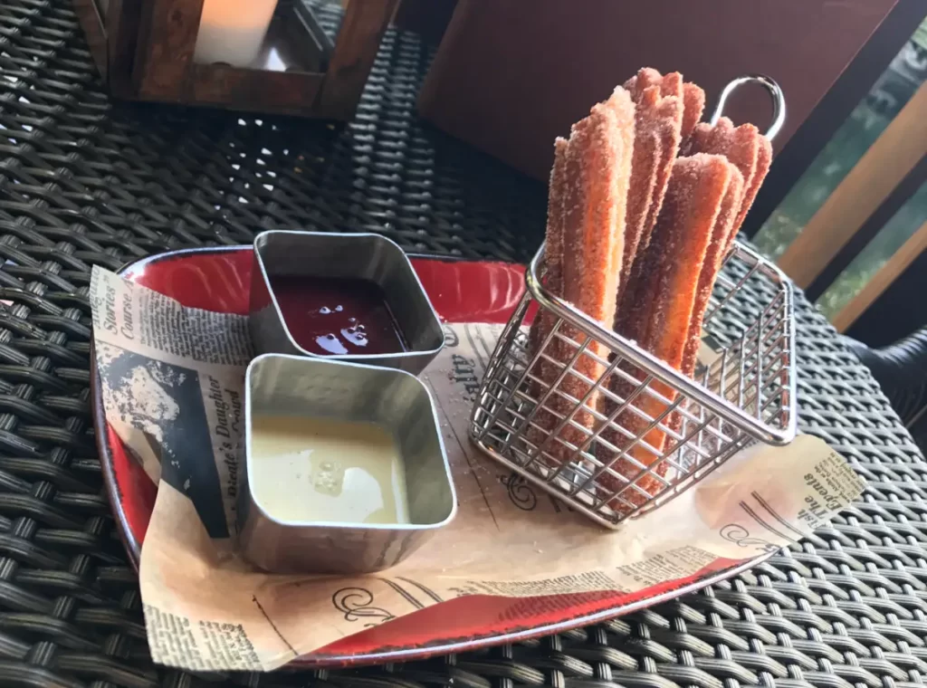Churros com açúcar e canela acompanhados de doce de leite e calda de frutas