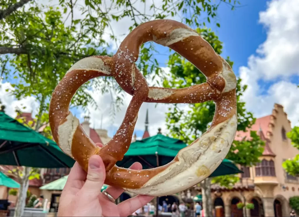 Pretzel gigante do pavilhão da Alemanha no EPCOT segurado com o parque ao fundo