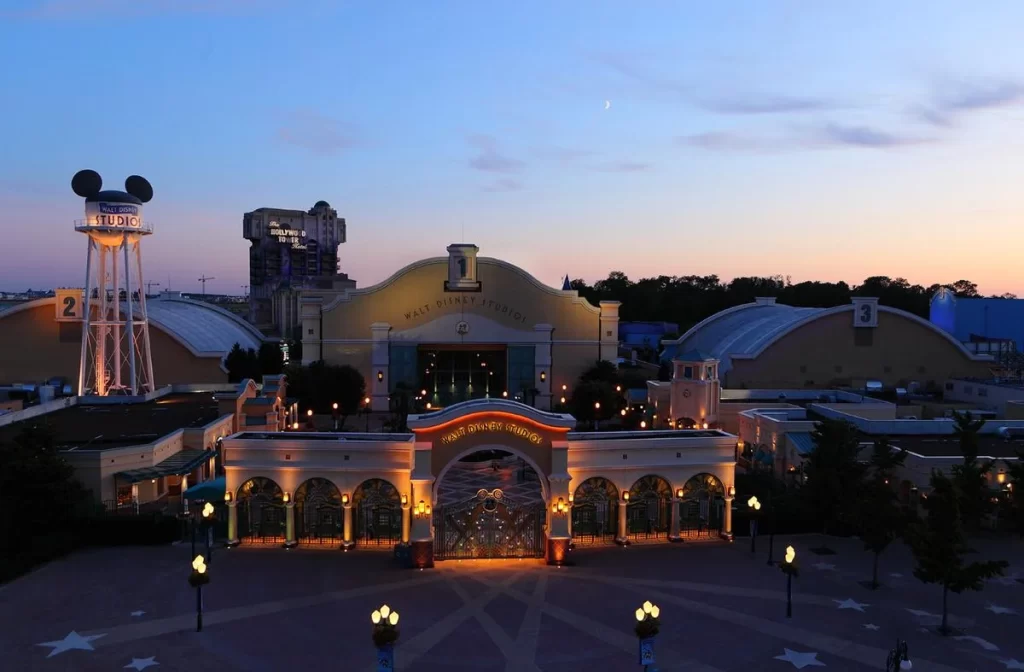Vista aérea do Walt Disney Studios Park iluminado ao anoitecer com céu azul escuro