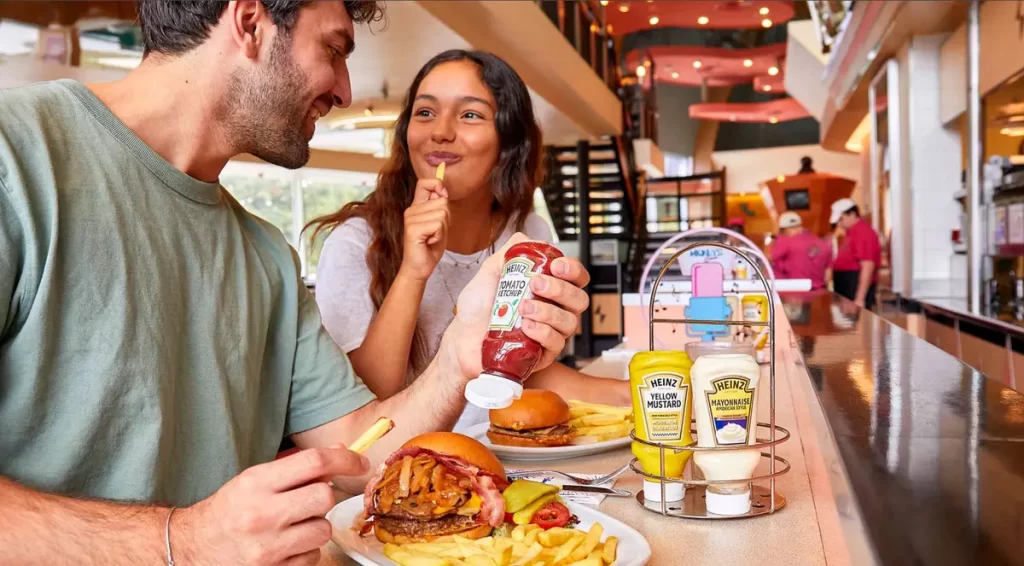 Casal saboreando hambúrguer com batatas fritas no Annette's Diner em Disneyland Paris