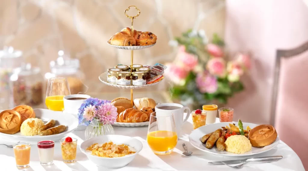 Café da manhã real com pães, sucos e pratos decorados no Auberge de Cendrillon