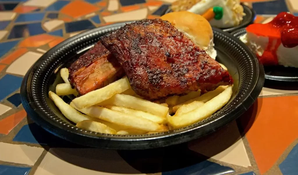 Costelas suculentas com batatas fritas e acompanhamentos.