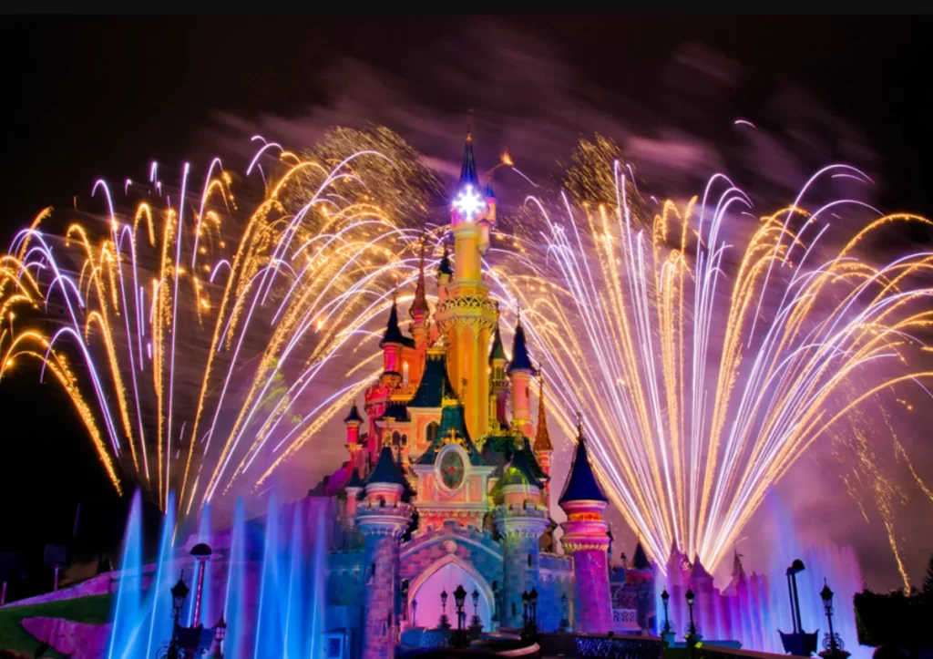 Fogos de artifício no céu sobre o Castelo da Bela Adormecida durante o show noturno da Disneyland Paris com águas dançantes.