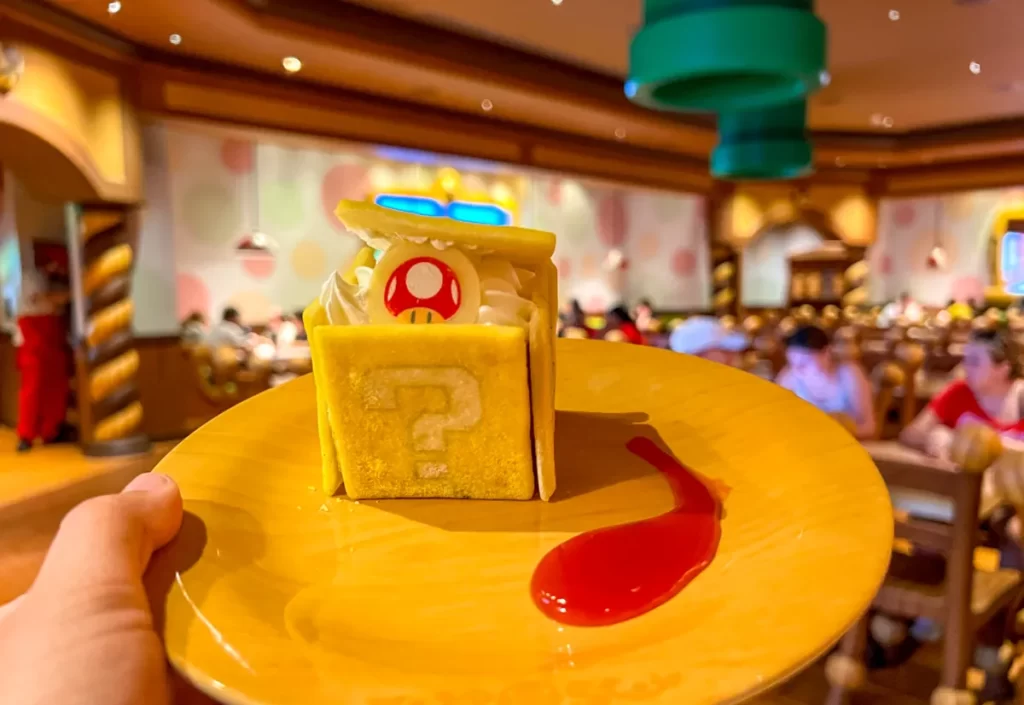 Sobremesa temática no Toadstool Café: cubo surpresa com recheio doce e apresentação divertida.