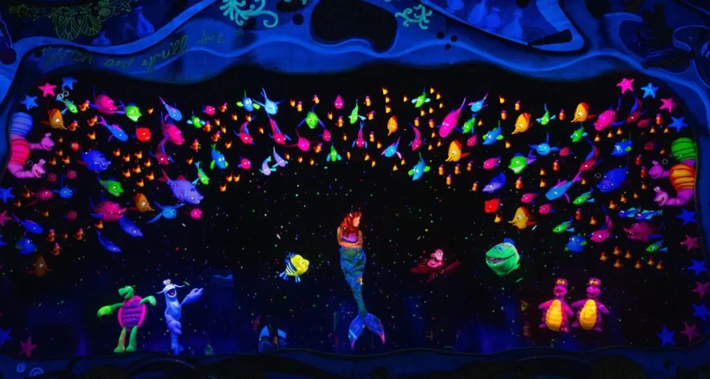 Ariel, Sebastião e peixes coloridos na cena Sob o Mar do musical A Pequena Sereia no Disney World Orlando.