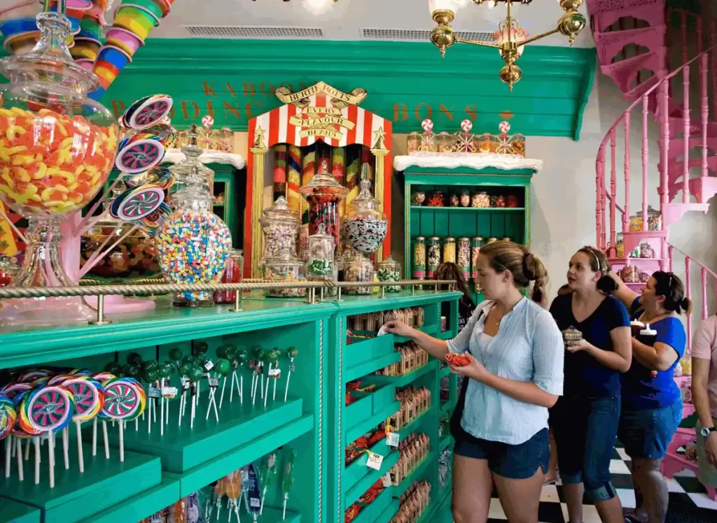 Interior da Honeydukes no Universal Orlando com prateleiras verdes, potes de doces mágicos e escada rosa em Hogsmeade