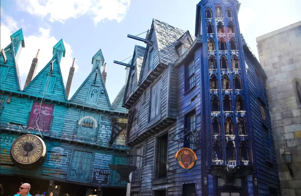 Fachadas azuladas e sombrias com corujas empoleiradas em vitrines na Knockturn Alley (Travessa do Tranco)