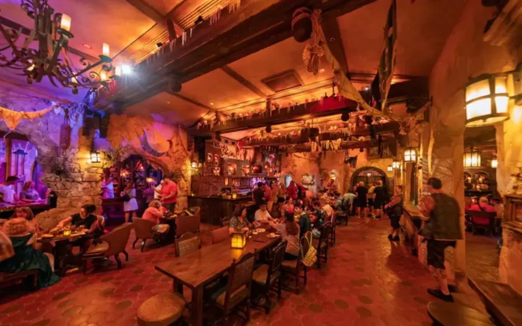 Interior temático da The Beak and the Barrel, restaurante estilo pirata com mesas iluminadas e decoração caribenha.