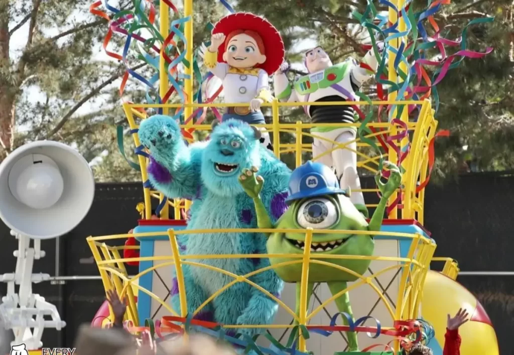 Personagens de Toy Story e Monstros S.A. em carro alegórico colorido durante a Pixar Play Parade da Disneyland.