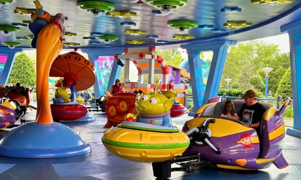 Passeio Alien Swirling Saucers no Toy Story Land da Disney, com carrinhos coloridos em formato de naves espaciais controladas por aliens verdes.