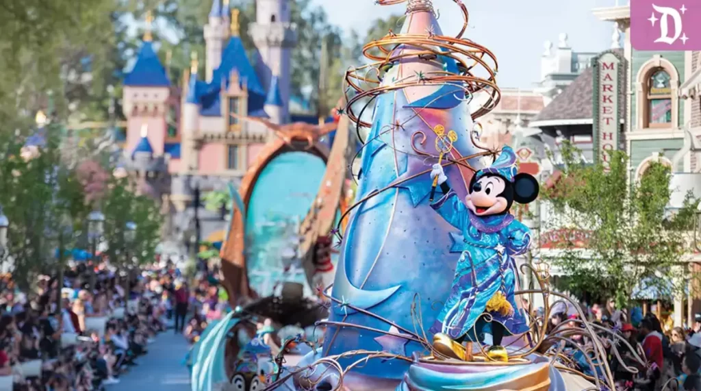 Mickey Feiticeiro com cajado dourado sobre carro alegórico azul e dourado no desfile Magic Happens da Disneyland.