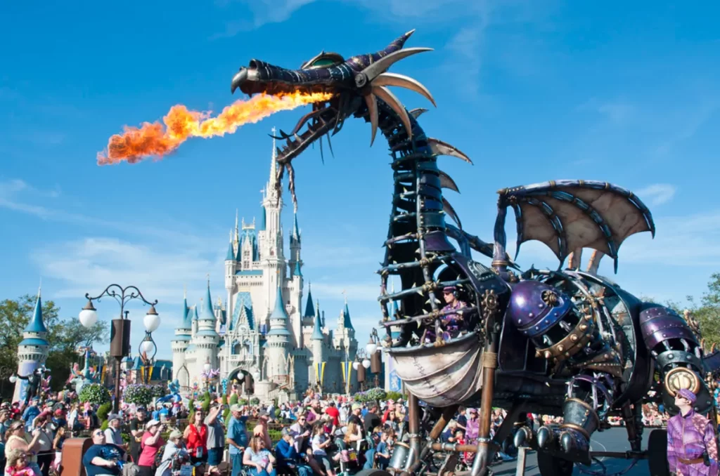 Carro alegórico da Maléfica em forma de dragão soltando fogo durante o desfile Disney Festival of Fantasy em frente ao Castelo da Cinderela.