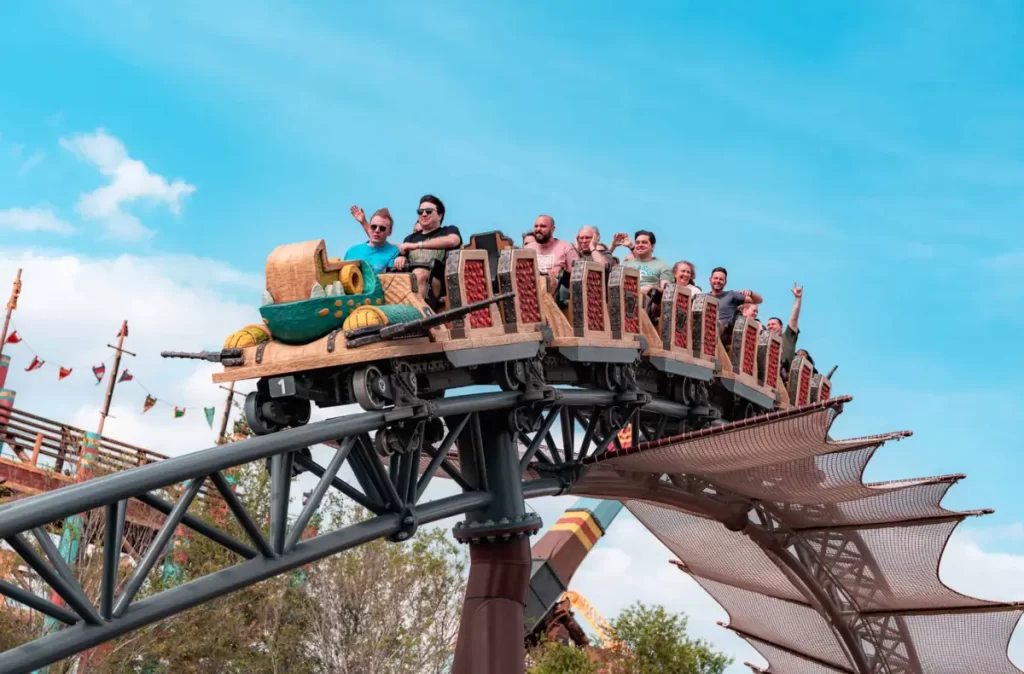 Visitantes no Hiccup’s Wing Gliders, montanha-russa familiar da Isle of Berk no Epic Universe, céu azul ao fundo.