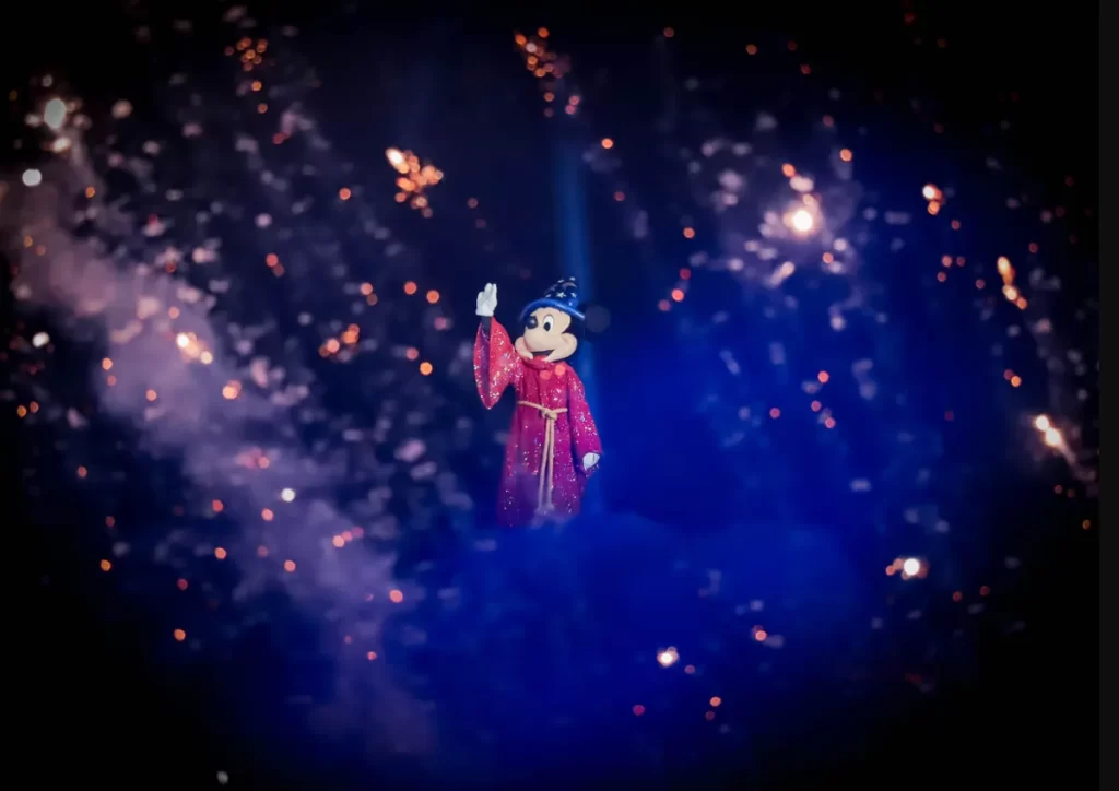 Mickey Mouse com traje de feiticeiro em Fantasmic!, iluminado por fogos e projeções mágicas no Disney’s Hollywood Studios.