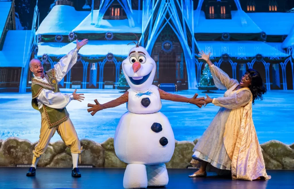 Show Frozen Sing-Along na Disney com Olaf e apresentadores em um cenário de inverno mágico.