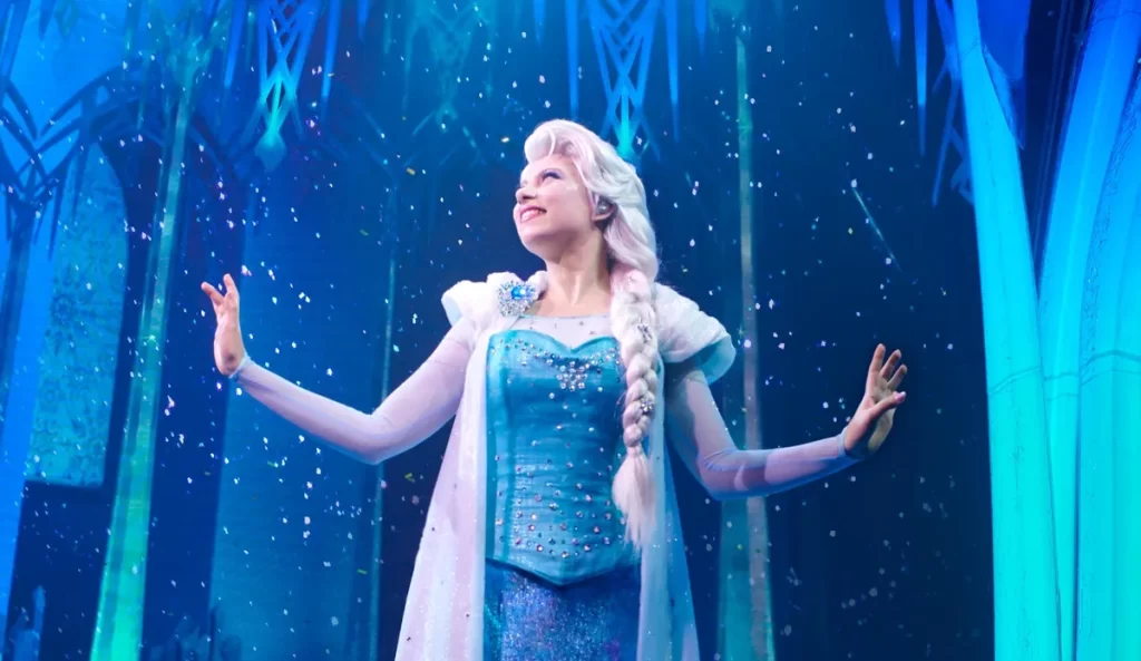 Elsa no palco do show Frozen: A Musical Invitation, atração encantadora da Disneyland Paris com neve e efeitos de luz mágicos.