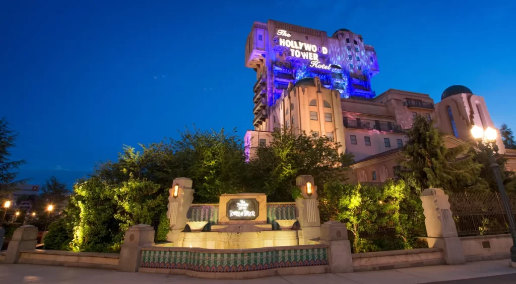 Atração Tower of Terror iluminada à noite no Walt Disney Studios Park, Disneyland Paris, com luzes roxas e fachada art déco.
