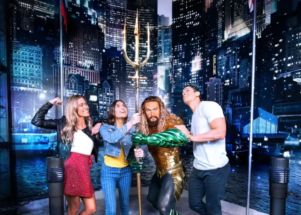 Visitantes posando com a estátua de cera de Aquaman interpretado por Jason Momoa no Madame Tussauds Orlando