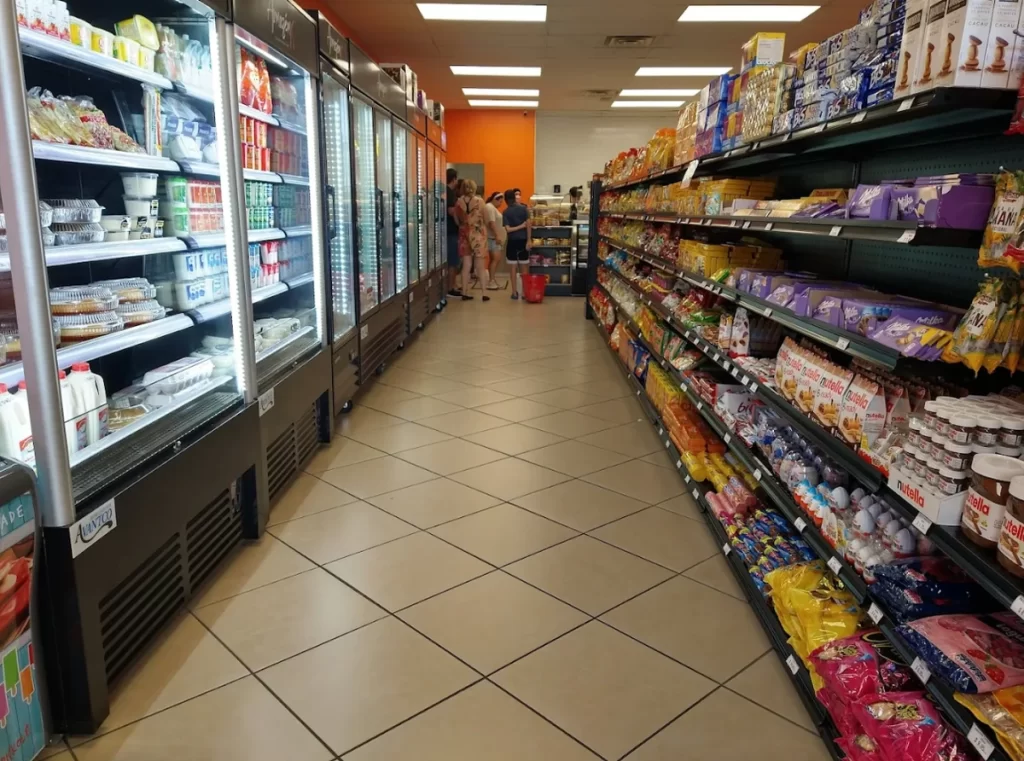 Corredor do Armazém X em Orlando com freezers de laticínios à esquerda e prateleiras de biscoitos à direita