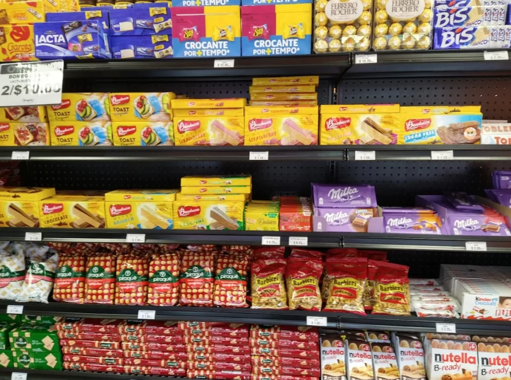 Prateleira do Armazém X em Orlando com biscoitos Bauducco, chocolates Milka e Kinder