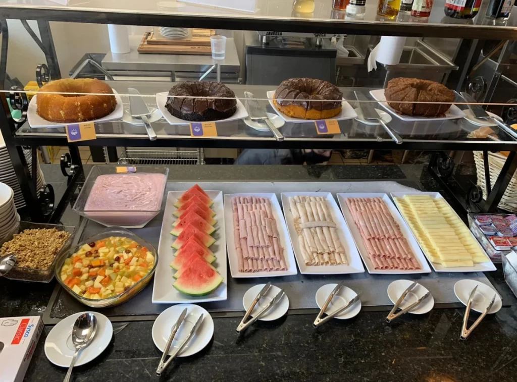 Café da manhã brasileiro no Rokka’s Market Orlando com bolos, frios e frutas