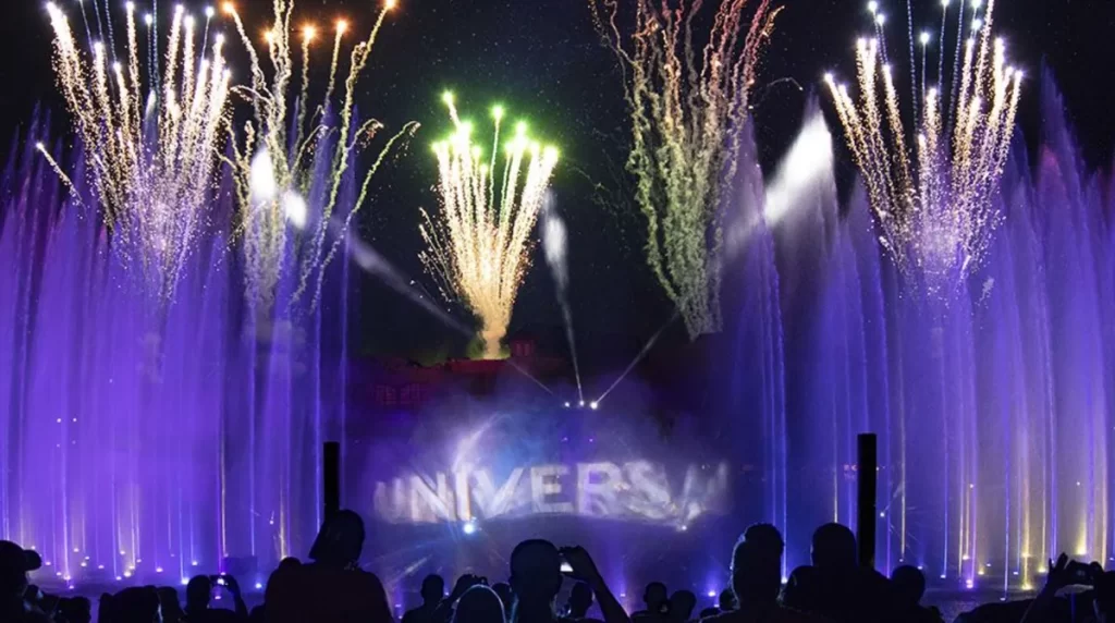 Show noturno no Universal Orlando com fogos de artifício, projeções de luz e fontes coloridas.