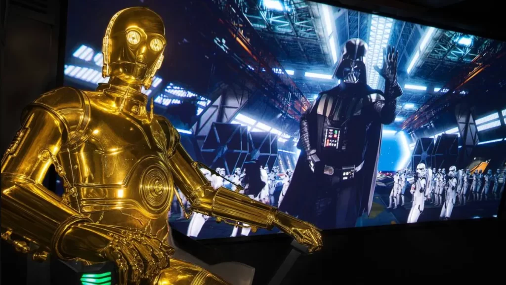 Atração Star Tours na Disney Hollywood Studios com C-3PO dourado e Darth Vader ao fundo com stormtroopers.