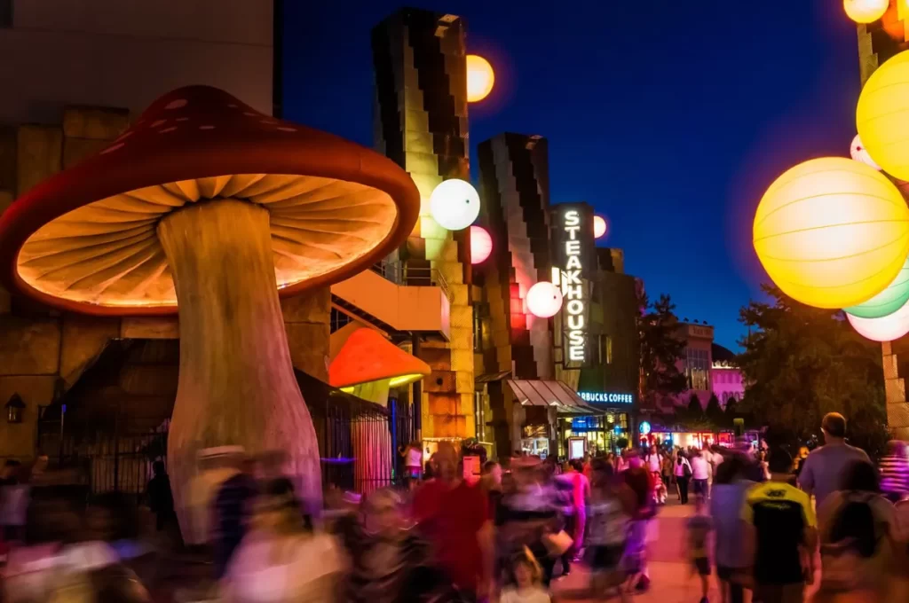Área movimentada com o restaurante Steakhouse e iluminação colorida no Disney Village Paris