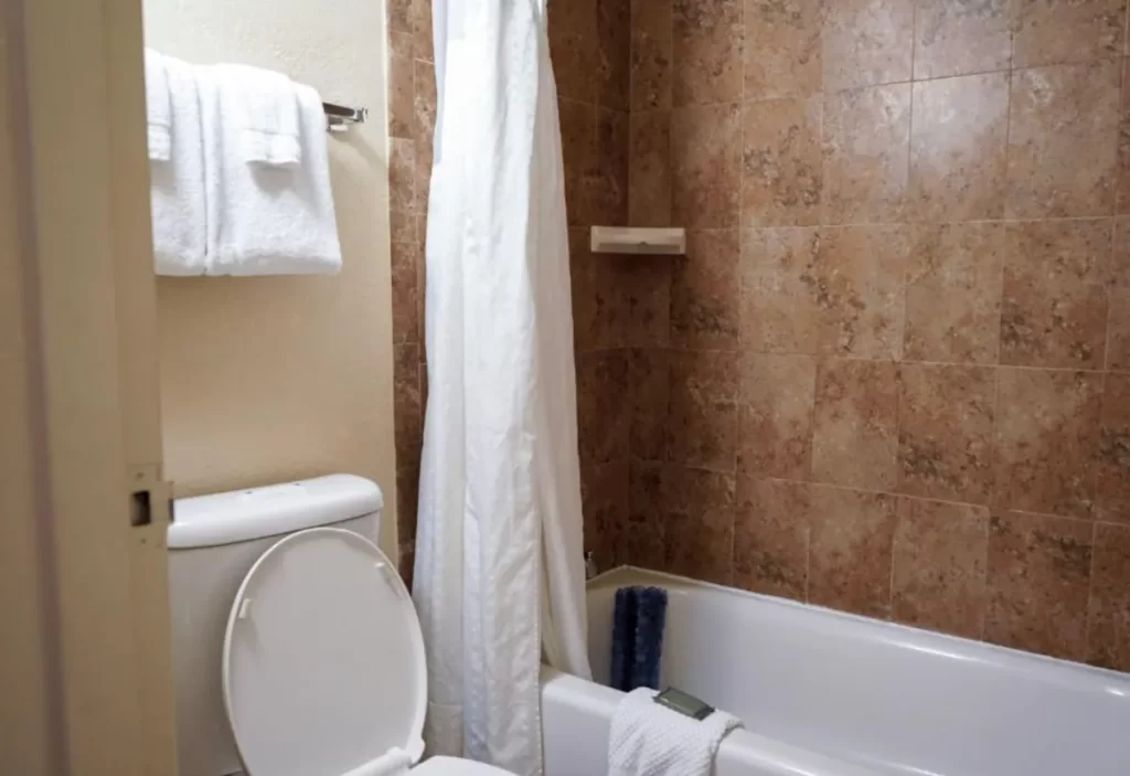 Banheiro do Rosen Inn International Drive com banheira, chuveiro e azulejos marmorizados.