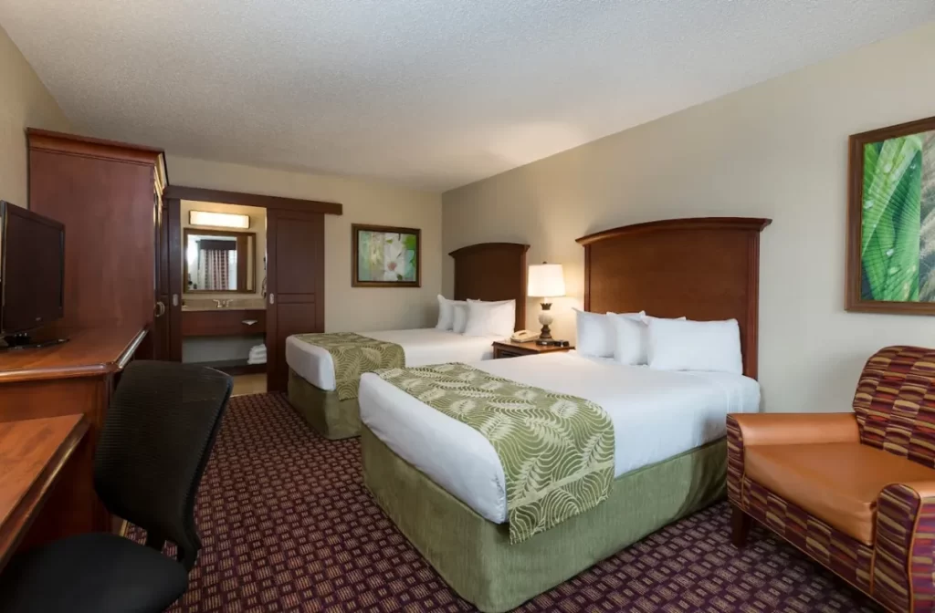 Quarto do Rosen Inn Pointe com duas camas, decoração clássica e área de pia integrada.