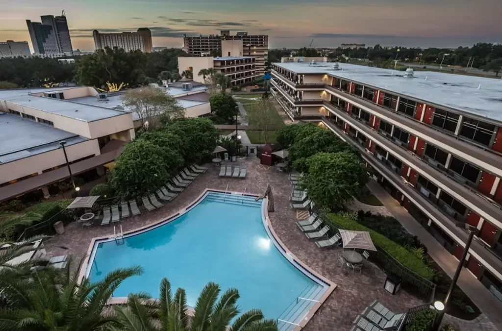 Vista aérea da piscina do Rosen Inn Pointe com espreguiçadeiras e prédios ao fundo.