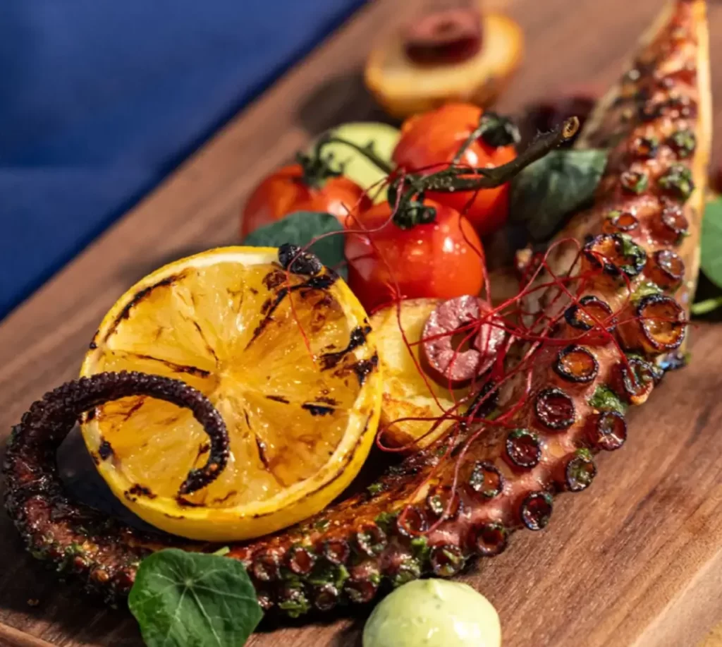 Prato gourmet servido no Helios Grand Hotel Epic Universe Orlando, com polvo grelhado, limão caramelizado e apresentação refinada