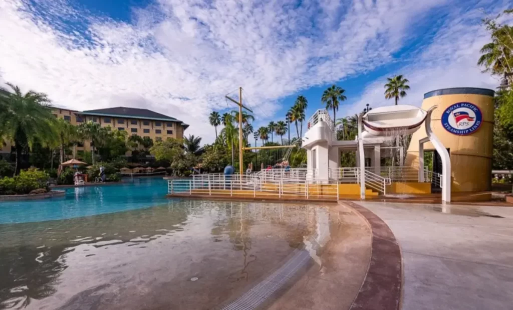 Área da piscina estilo lagoa do Loews Royal Pacific Resort no Universal Orlando, com playground aquático, palmeiras e ambiente perfeito para famílias.