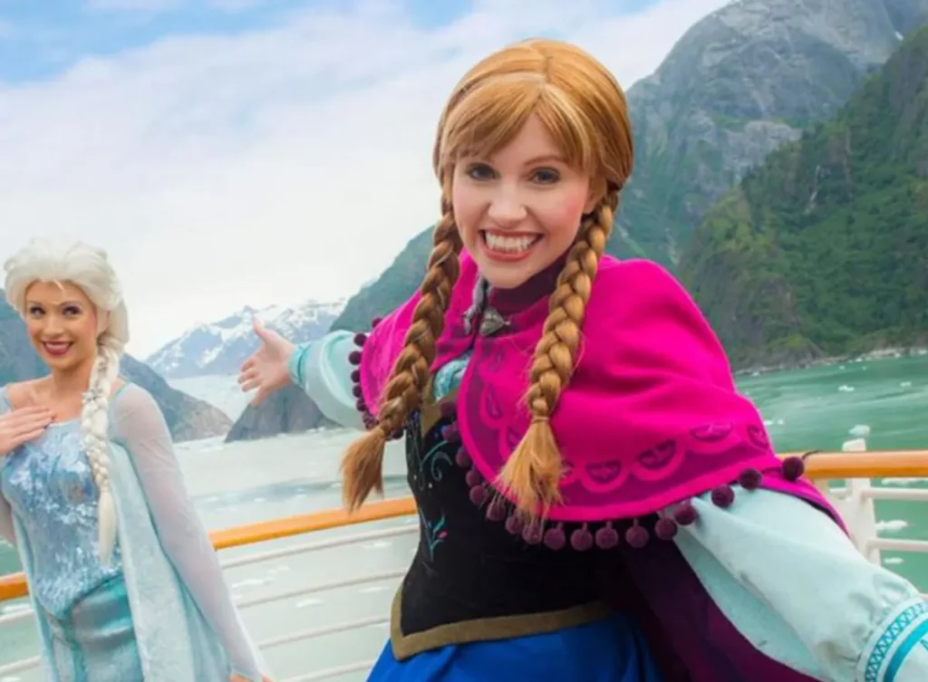 Anna e Elsa do Frozen no deck do navio com paisagem do Alasca ao fundo.